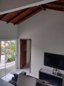 a living room with a couch and a tv on a wall at Casa praia do Forte in Florianópolis