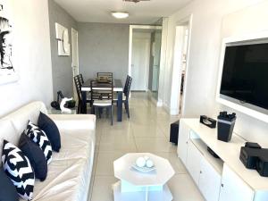 ein Wohnzimmer mit einem weißen Sofa und einem Tisch in der Unterkunft MARCOLINI - Luxo Vista Mar - Praia do Pepê in Rio de Janeiro