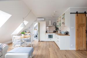 a kitchen and dining room with white cabinets and a table at Apartament Bulvar Starówka in Elblag