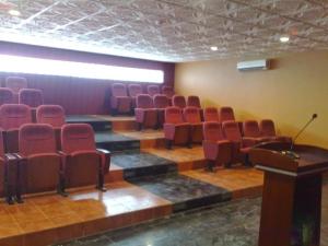 a lecture room with red chairs and a podium at روائع للشقق المخدومة in Taif