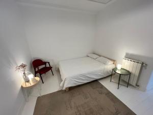 - une chambre blanche avec un lit et une chaise rouge dans l'établissement Luminoso apartamento en el centro de San Sebastián, à Saint-Sébastien