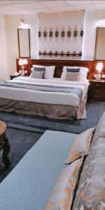 a hotel room with two beds and two tables at روائع للشقق المخدومة in Taif