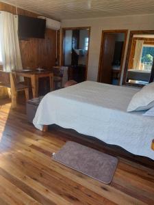 a bedroom with a large bed and a table at Pousada Recanto do Lago in Cambará