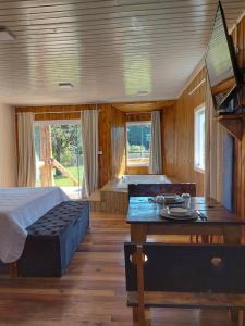 Schlafzimmer mit einem Bett, einem Tisch und Fenstern in der Unterkunft Pousada Recanto do Lago in Cambará