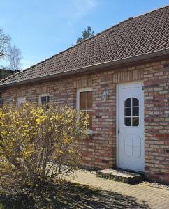 un edificio de ladrillo con una puerta blanca. en Ferienwohnungen Rügen-Glück en Lohme