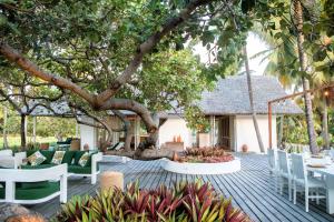 a patio with tables and chairs under a tree at Ananda Atins in Atins