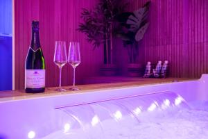 - une bouteille de vin assise sur un comptoir avec 2 verres à vin dans l'établissement Art Déco Champagne & Spa, à Reims