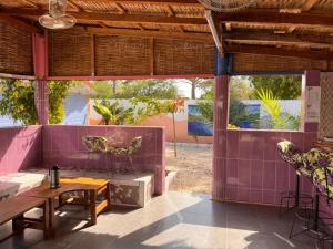 Habitación con pared morada, mesa y sillas. en Nouvelle vision des coquillages CHEZ NABOU, en Toubakouta
