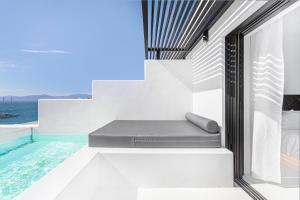 a balcony with a bench next to a swimming pool at Tagoo Black Mykonos in Mikonos