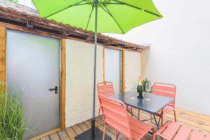 a table and chairs with a green umbrella on a patio at Art Déco Champagne & Spa in Reims