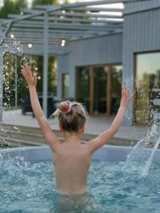 Una joven en una piscina con los brazos en alto. en Dabas Osta, en Jūdaži