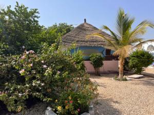 einen Pavillon mit einer Palme und ein paar Blumen in der Unterkunft Nouvelle vision des coquillages CHEZ NABOU in Toubakouta