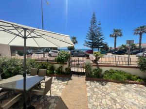 a table with an umbrella next to a parking lot at Casa 1ª linea de playa Benajarafe in Benajarafe