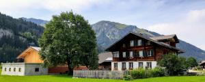una casa in un campo con un albero e una montagna di Bühlerhof a Lenk