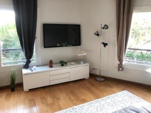 a white living room with a flat screen tv on the wall at Studio Moderne & Cosy Proche Paris in Rosny-sous-Bois