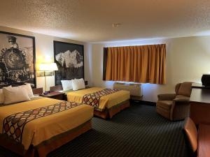 a hotel room with two beds and a chair at Super 8 by Wyndham Trinidad in Trinidad