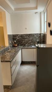 La cuisine est équipée de comptoirs en granit et d'un réfrigérateur noir. dans l'établissement Tiwaline Tarsime App C, à Sidi Ifni