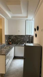 une cuisine avec des armoires blanches et un réfrigérateur noir dans l'établissement Tiwaline Tarsime App C, à Sidi Ifni