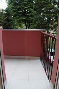 a balcony with a red fence and trees at Emerald Suite in Valjevo