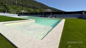 a swimming pool with water in a grass field at Casas Manos Névoa in Geres