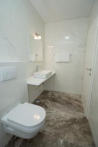 a white bathroom with a toilet and a sink at Villa Lucini Dvori in Novalja