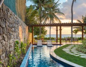 a swimming pool with chairs and a stone wall at Serrambi Resort in Porto De Galinhas