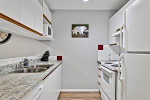 a white kitchen with a sink and a refrigerator at The Norquay, Pet-Friendly 2 Bed with Mtn View in Canmore +18 photos