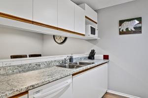 a kitchen with white cabinets and a sink at The Norquay, Pet-Friendly 2 Bed with Mtn View in Canmore