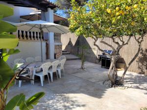einen Tisch und Stühle mit einem Sonnenschirm und einem Orangenbaum in der Unterkunft Villa Corazón in Capdepera