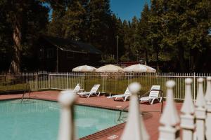 ein Pool mit Stühlen und Sonnenschirmen neben einem Zaun in der Unterkunft The Long Barn Lodge in Long Barn