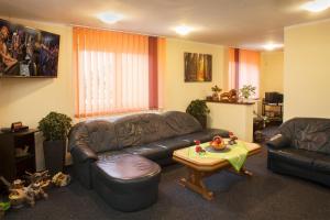 ein Wohnzimmer mit einem Ledersofa und einem Tisch in der Unterkunft Pension RELAX U Komína in Franzensbad