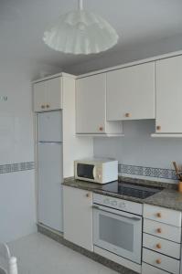 Precioso apartamento de 3 habitaciones en Cabañas. في كاباناس: مطبخ مع دواليب بيضاء وميكرويف