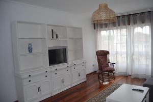 Precioso apartamento de 3 habitaciones en Cabañas. في كاباناس: غرفة معيشة مع تلفزيون في خزانة بيضاء