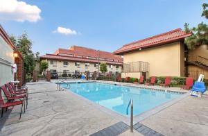a swimming pool in a courtyard with chairs and a building at Red Roof Inn Santa Ana in Santa Ana