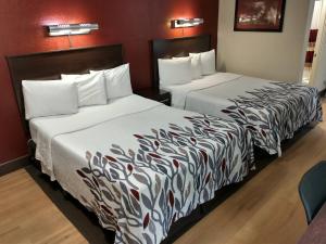 2 camas en una habitación de hotel con sábanas blancas en Red Roof Inn Santa Ana en Santa Ana