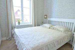 uma cama branca num quarto branco com uma janela em Lovely 2-bedroom apartment with free parking em Haapsalu