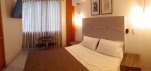 um quarto com uma cama com lençóis brancos e uma janela em LUMA SUITE em Lima