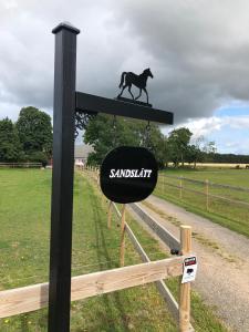 um sinal com um cavalo correndo sobre uma cerca em Lilla Sandslätt em Åhus