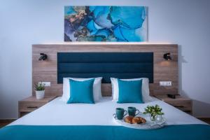 a bed with blue pillows and a plate of food on it at Floral Hotel in Hersonissos