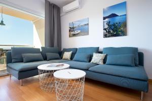 V016 - SUN VILLAGE في Palau-Saverdera: غرفة معيشة مع أريكة زرقاء وطاولتين