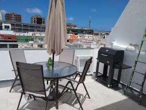 einen Glastisch und Stühle auf einem Balkon mit Grill in der Unterkunft Edificio Triana St 47 in Las Palmas de Gran Canaria