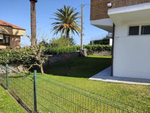 a fence in front of a yard with a palm tree at Casa vacacional La Terrona in Trasvia