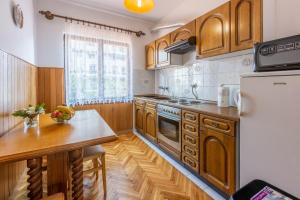 a kitchen with wooden cabinets and a refrigerator at Apartment Arya in Crikvenica