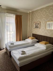 a hotel room with three beds and a window at Apartamenty Centrum in Olkusz