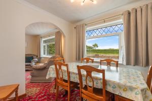 a dining room with a table and a large window at Trefelyn Cottage in Saundersfoot