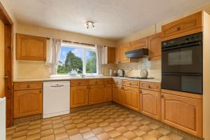 a kitchen with wooden cabinets and a window at Trefelyn Cottage in Saundersfoot +15 photos