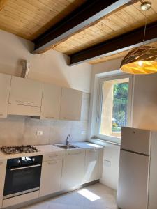cocina con armarios blancos, fregadero y ventana en Residence La MARCHINA, en Castel Bolognese