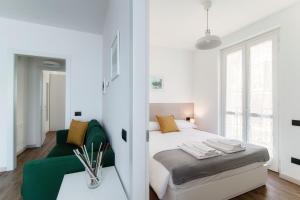 a white bedroom with a bed and a green couch at The view apartment 2 in Bellagio