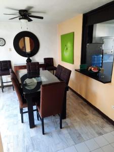 a dining room with a table and chairs and a television at Villa Quintas Del Mar in Mazatlán