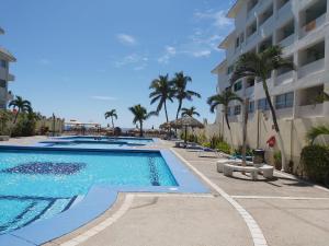 een zwembad naast een gebouw met palmbomen bij Villa Quintas Del Mar in Mazatlán